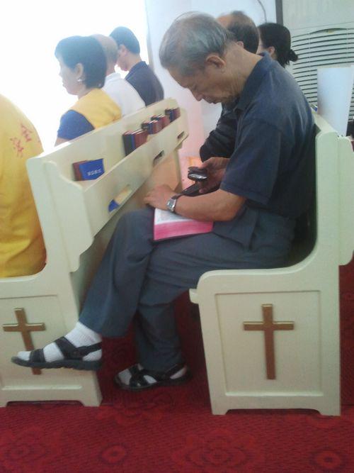 一位老弟兄在正拿着放大镜吃力看着《圣经》。(图:张胜虎弟兄提供)