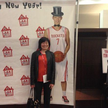 林妈妈站在儿子林书豪“Happy New Year”的海报前的照片(图片来源:林书豪新浪微博)